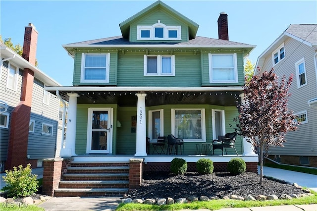 american foursquare style home featuring a porch and a chimney