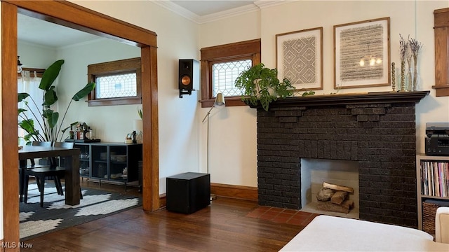 sitting room featuring crown molding, a brick fireplace, baseboards, and dark wood finished floors