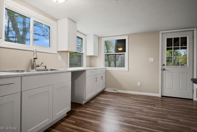 5331 Ridgewood St, Lorain, OH 44055 - kitchen with a textured ceiling, dark wood finished floors, visible vents, a sink, and white cabinets