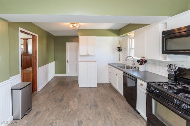 3019 Clague Rd, North Olmsted, OH 44070 - kitchen with white cabinetry, black appliances, a wainscoted wall, and a sink