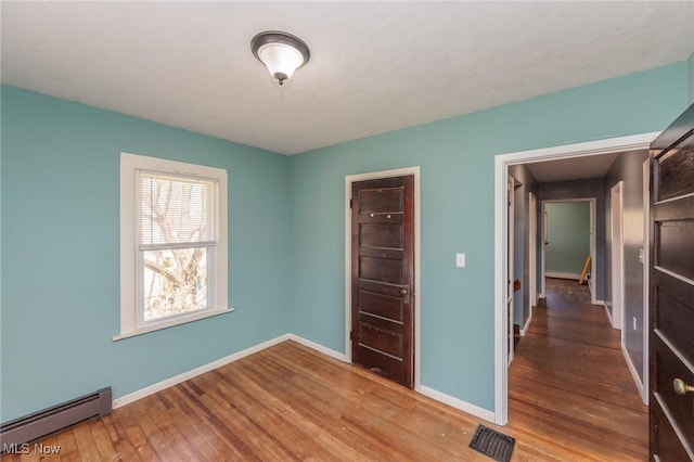 3019 Clague Rd, North Olmsted, OH 44070 - unfurnished bedroom with a baseboard radiator, baseboards, visible vents, and wood finished floors