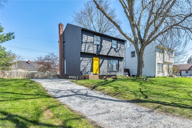 colonial house with entry steps, a front lawn, and driveway