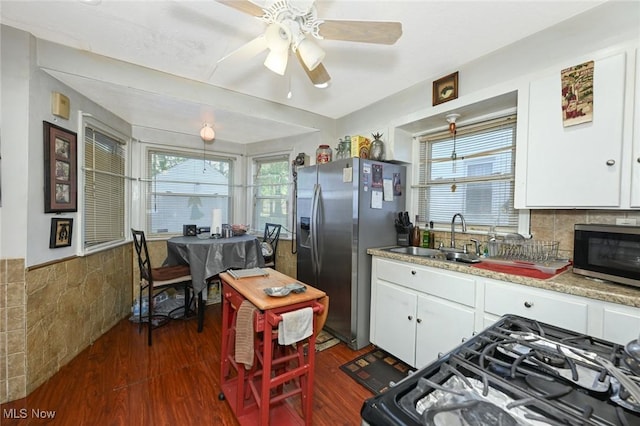 kitchen with a sink, stainless steel appliances, white cabinetry, dark wood-type flooring, and light countertops