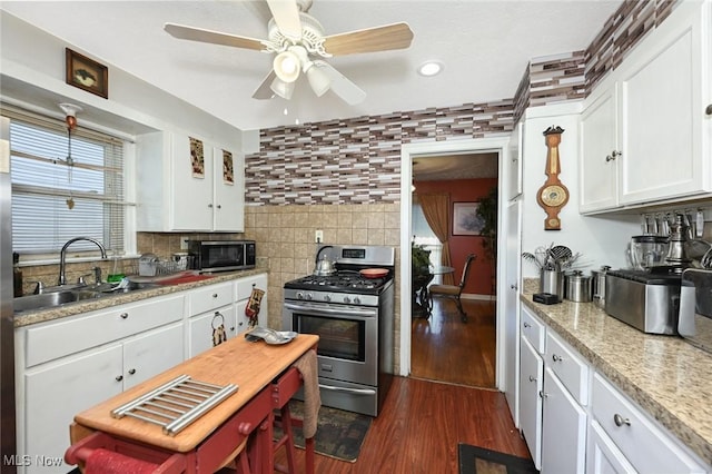 kitchen featuring a sink, stainless steel appliances, dark wood finished floors, ceiling fan, and white cabinetry