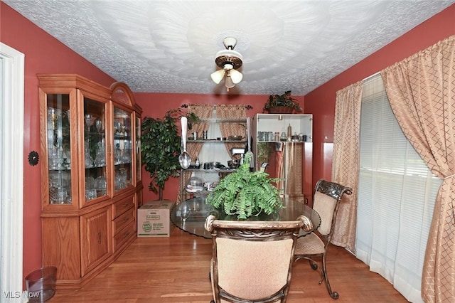 dining area featuring a textured ceiling, wood finished floors, and ceiling fan