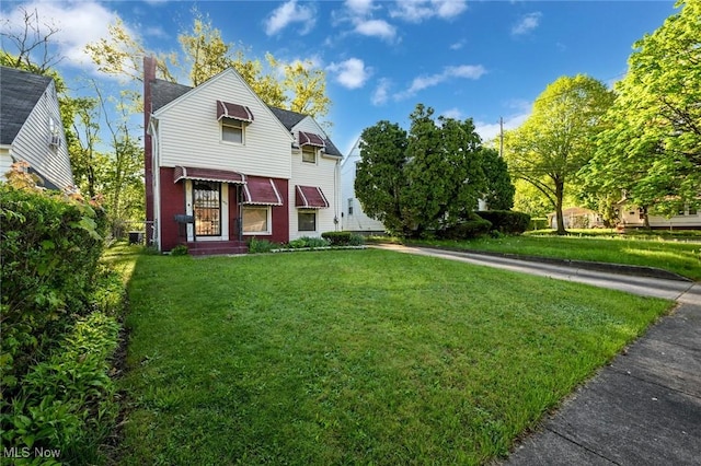 victorian home featuring a chimney, brick siding, and a front lawn
