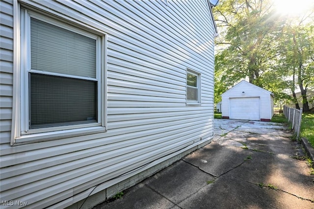 view of home's exterior featuring an outbuilding, driveway, fence, and a detached garage