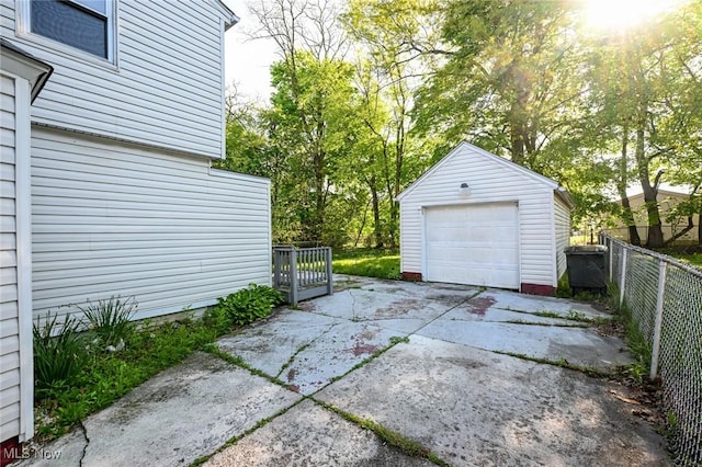 detached garage featuring concrete driveway and fence
