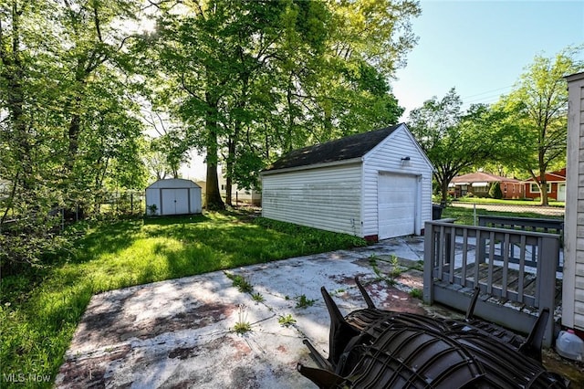 detached garage featuring fence, a shed, and driveway