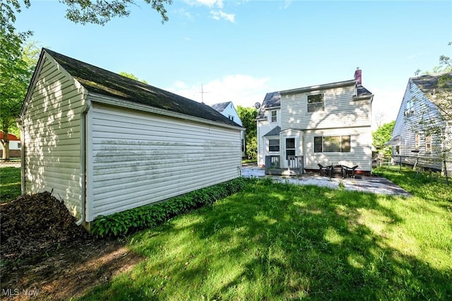 rear view of property featuring a patio area, fence, a chimney, and a lawn