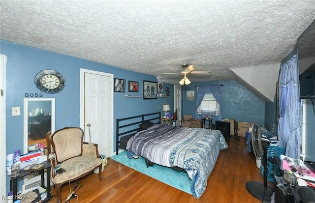 bedroom with ceiling fan, a textured ceiling, lofted ceiling, and wood finished floors