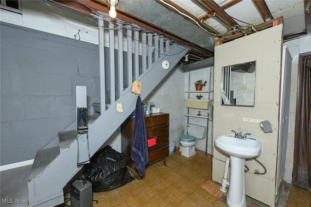 bathroom featuring toilet and concrete block wall