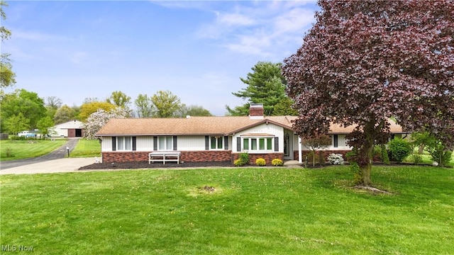ranch-style home featuring a chimney, brick siding, and a front lawn