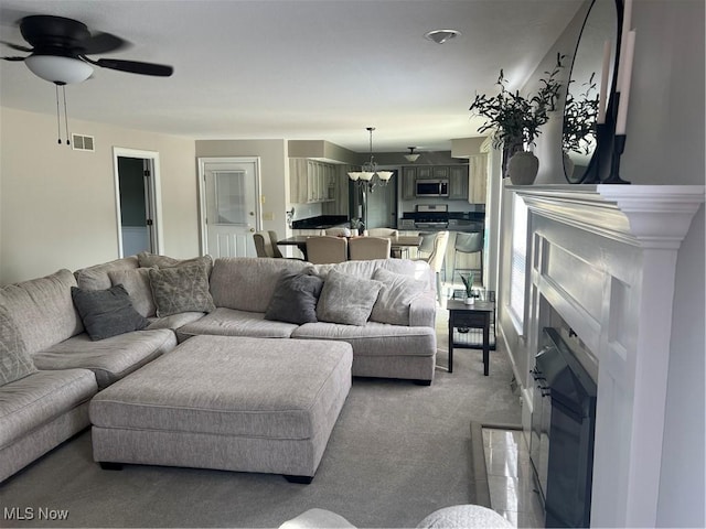 7966 Meadowbrooke Trl, Poland, OH 44514 - living area with light colored carpet, visible vents, a fireplace, and ceiling fan with notable chandelier