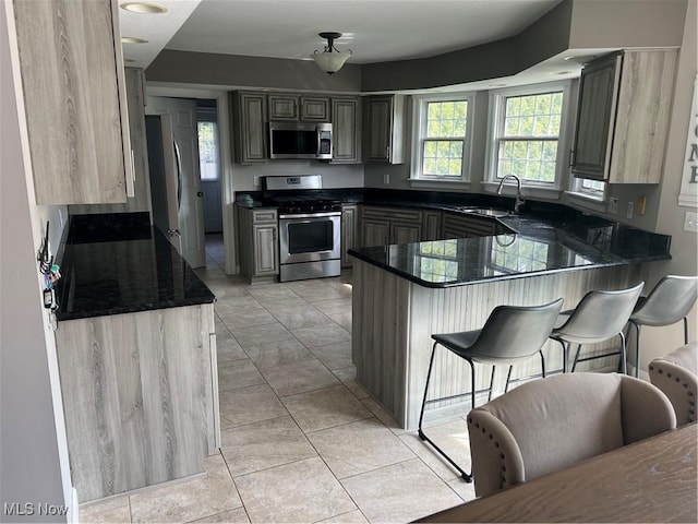 7966 Meadowbrooke Trl, Poland, OH 44514 - kitchen featuring a breakfast bar area, light tile patterned floors, a sink, a peninsula, and appliances with stainless steel finishes