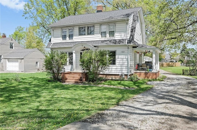 view of front facade with a chimney, a porch, a shingled roof, and a front lawn