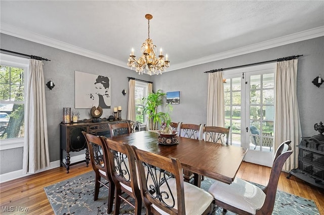 dining space featuring light wood finished floors, a healthy amount of sunlight, and an inviting chandelier