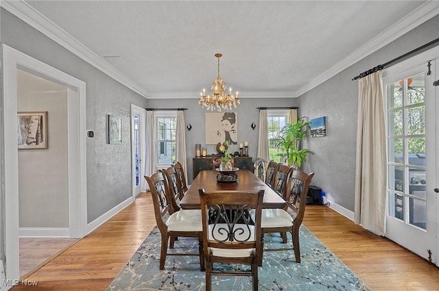dining space featuring baseboards, light wood-style floors, a chandelier, and crown molding