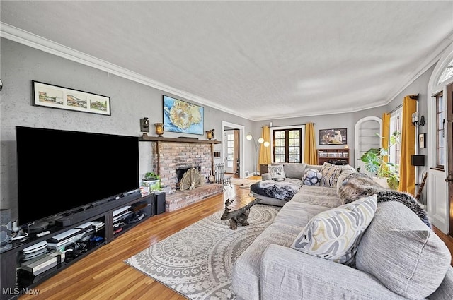 living area featuring crown molding, wood finished floors, and a fireplace