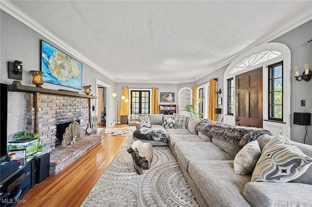living area with a fireplace, crown molding, a textured ceiling, and wood finished floors