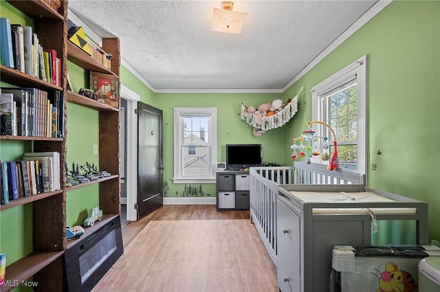 interior space with crown molding, a textured ceiling, baseboards, and light wood-style floors