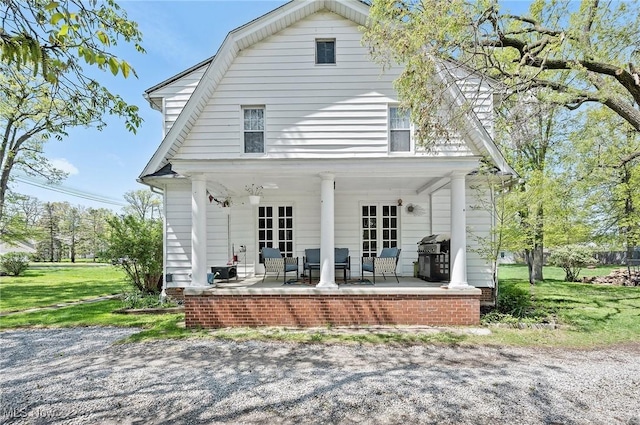 rear view of property featuring a gambrel roof and a porch