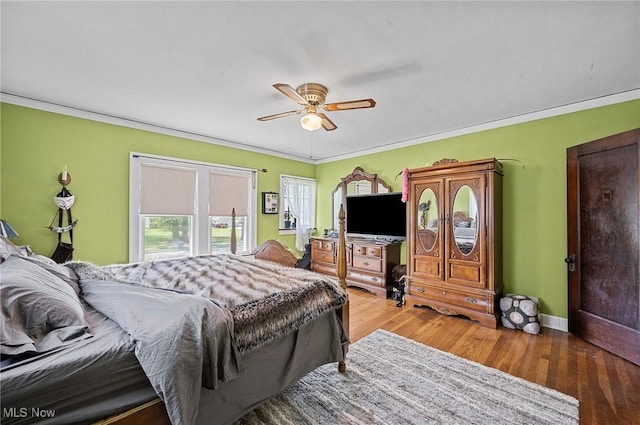 bedroom with crown molding, baseboards, wood finished floors, and a ceiling fan