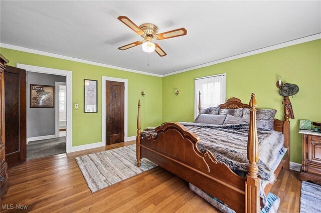 bedroom with baseboards, crown molding, a ceiling fan, and wood finished floors