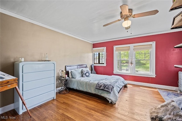bedroom featuring crown molding, wood finished floors, baseboards, and ceiling fan
