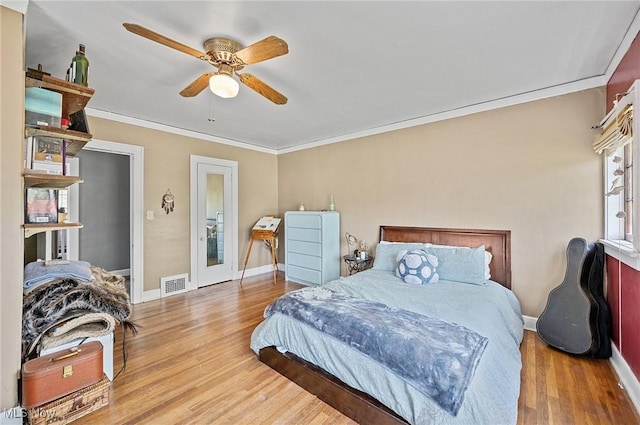 bedroom with crown molding, baseboards, visible vents, and wood finished floors