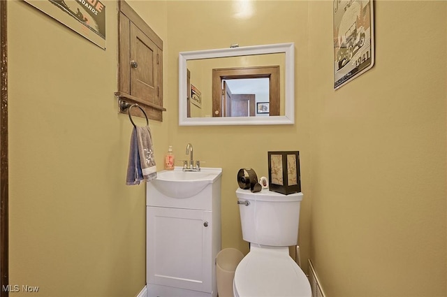 half bath featuring vanity, toilet, and baseboards