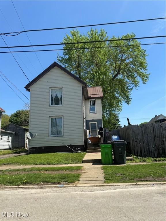 view of front of property with a front yard, metal roof, and fence
