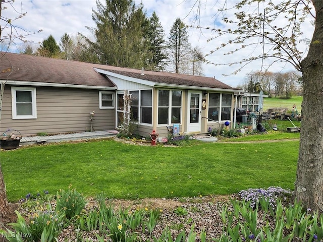 back of house with a sunroom, a shingled roof, and a lawn