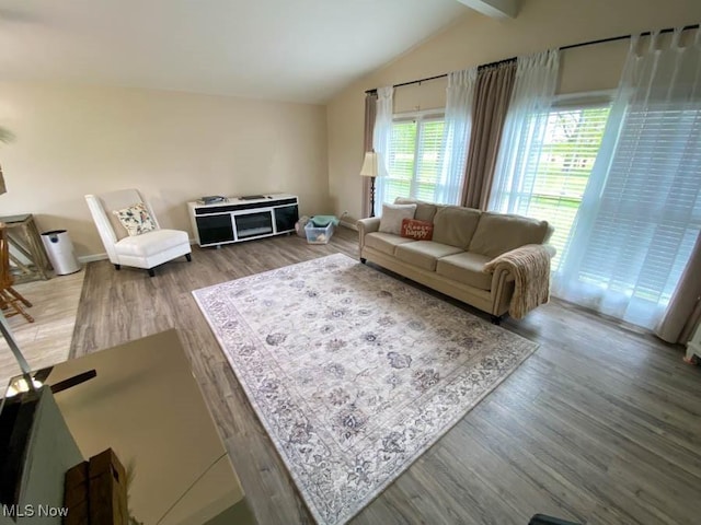 living area with lofted ceiling with beams and wood finished floors