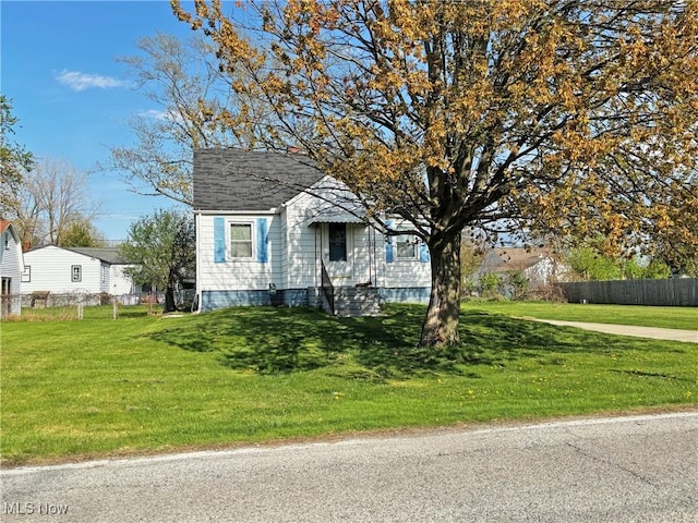bungalow-style house featuring a front lawn, roof with shingles, and fence