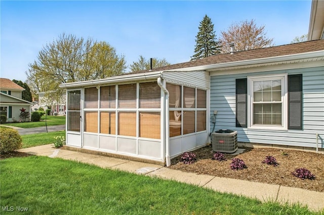 view of home's exterior featuring central air condition unit, a sunroom, and a lawn