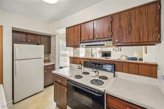 kitchen with freestanding refrigerator, light countertops, electric stove, and under cabinet range hood