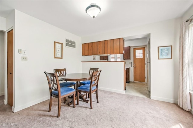 dining room with light colored carpet, baseboards, and visible vents