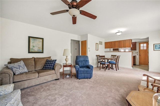 living area with light carpet, baseboards, and a ceiling fan