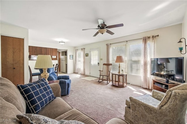 living area with light colored carpet and a ceiling fan