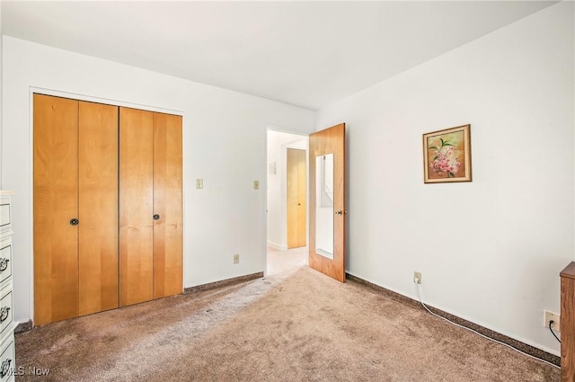 unfurnished bedroom with light colored carpet, a closet, and baseboards