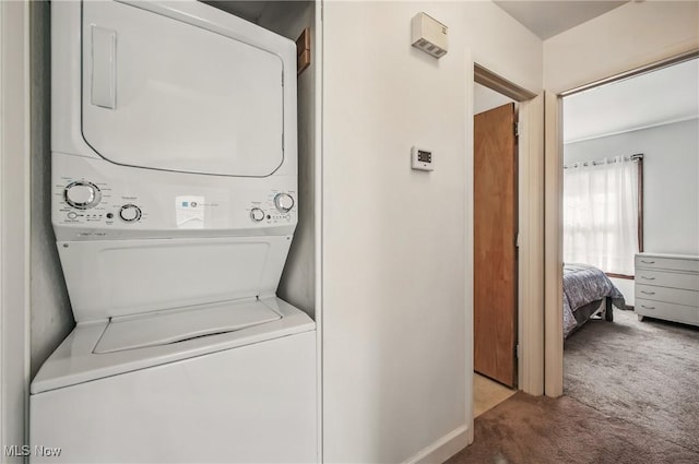 washroom featuring carpet, baseboards, and stacked washer and dryer