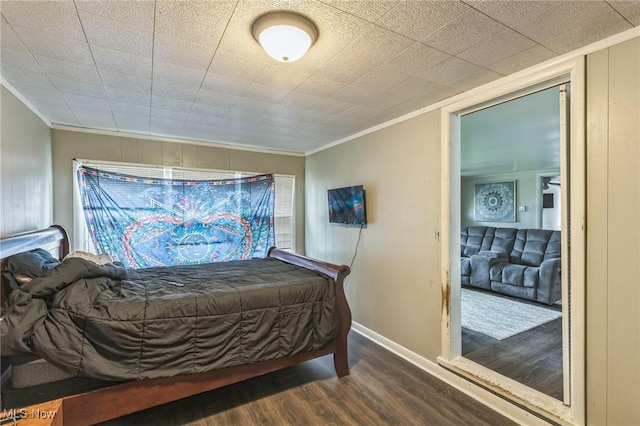 bedroom featuring ornamental molding, baseboards, and wood finished floors