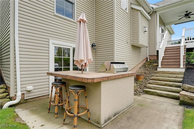 view of patio / terrace with area for grilling, outdoor wet bar, exterior kitchen, stairway, and a ceiling fan