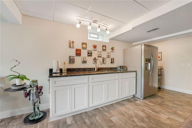 kitchen featuring visible vents, a sink, white cabinetry, stainless steel fridge, and light wood-type flooring