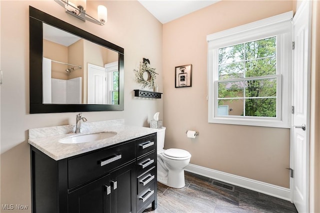 full bath featuring baseboards, toilet, walk in shower, visible vents, and vanity