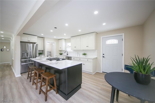 6544 Nancy Dr, North Olmsted, OH 44070 - kitchen featuring a breakfast bar area, a kitchen island, light countertops, white cabinets, and appliances with stainless steel finishes