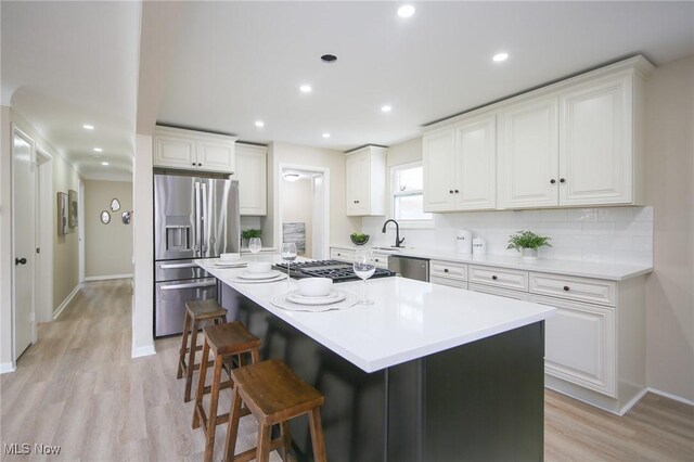 6544 Nancy Dr, North Olmsted, OH 44070 - kitchen featuring stainless steel appliances, baseboards, light wood finished floors, white cabinets, and a kitchen island