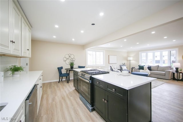 6544 Nancy Dr, North Olmsted, OH 44070 - kitchen featuring a center island, white cabinetry, light wood-style floors, light countertops, and appliances with stainless steel finishes