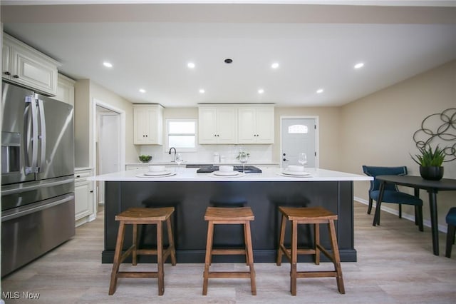 6544 Nancy Dr, North Olmsted, OH 44070 - kitchen with a center island, a sink, a breakfast bar, stainless steel refrigerator with ice dispenser, and light countertops